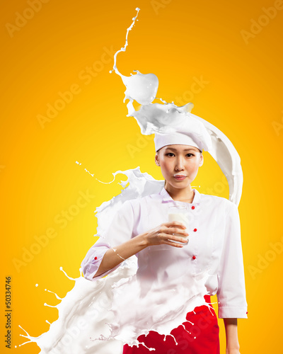 Photo: Asian female cook against milk splashes Asian female cook against milk splashes