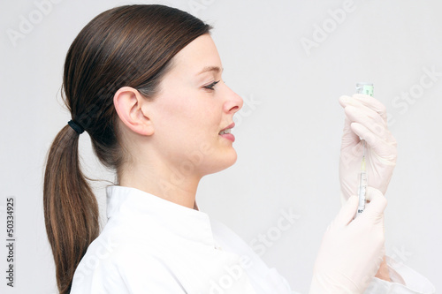Photo: junge Ärztin zieht Spritze auf junge Ärztin zieht Spritze auf