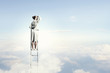 Businesswoman standing on ladder