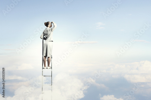 Photo: Businesswoman standing on ladder Businesswoman standing on ladder