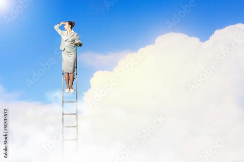 Photo: Businesswoman standing on ladder Businesswoman standing on ladder