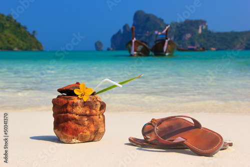 Photo: Coconut cocktail and sandals on the beach Coconut cocktail and sandals on the beach