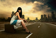 Young woman waiting on the road with her vintage baggage