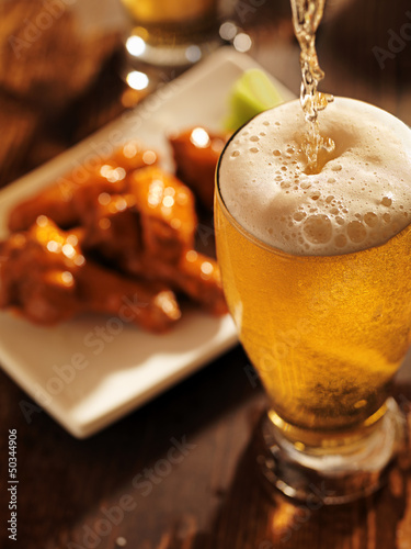 Photo: pouring beer with chicken wings in background. pouring beer with chicken wings in background.