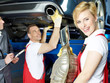 A team of car mechanics fixing the exhaust system of a car