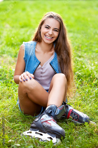 Photo: girl wearing roller skates sitting on grass girl wearing roller skates sitting on grass