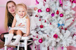 The little girl with ðîäèòåëÿìèó a white Christmas fir-tree