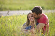 A young couple sitting in long grass embracing