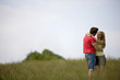 A young couple standing in a field embracing