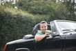 A young man sitting in a black sports car