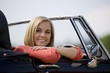 A young woman sitting in a black sports car