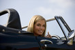 A young woman in a sports car holding a lipstick