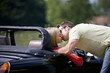A young man kissing a young woman in a black sports car