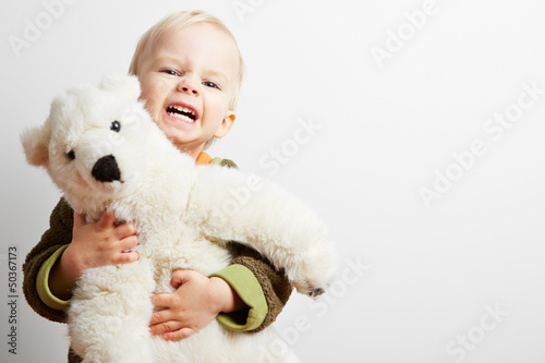 Photo: Junge hält grimmig sein Stofftier fest Junge hält grimmig sein Stofftier fest