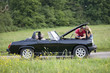 A young couple standing next to their broken down sports car