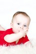 Thoughtful six-months baby holds fingers in mouth