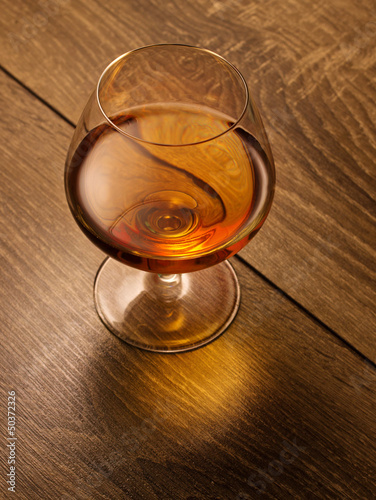 Photo: brandy glass on a wooden table brandy glass on a wooden table