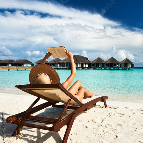 Photo: Young woman reading a book at beach Young woman reading a book at beach