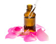 Fläschchen Rosenöl mit Rosenblättern und Pipette