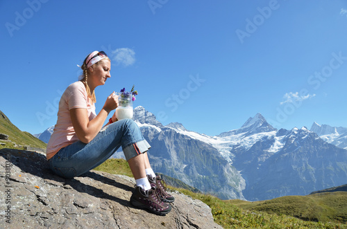 Photo: Girl holding a jug of milk and flowers against Swiss Alps Girl holding a jug of milk and flowers against Swiss Alps