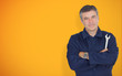 Mature mechanic standing in front of yellow background