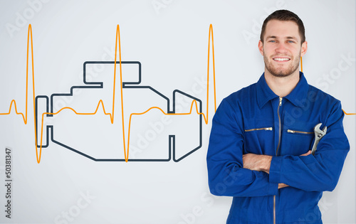Photo: Portrait of a young mechanic next to background with car engine Portrait of a young mechanic next to background with car engine
