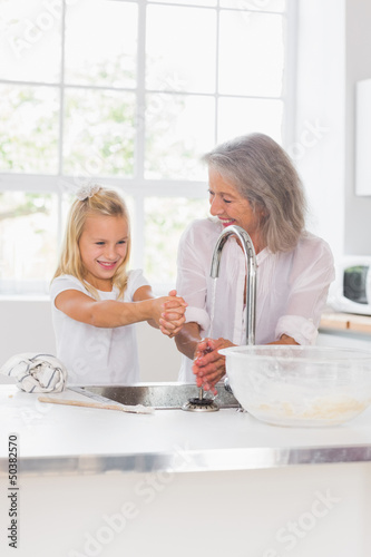 Photo: Smiling grandmother and granddaughter washing hands Smiling grandmother and granddaughter washing hands