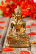 Goldener Buddha vor rote Blüten
