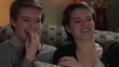 Twin sisters watching a comedy together eating popcorn