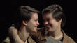 Twin sisters looking at each other with arm around shoulder