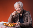 Senior woman tasting apple pie on an orange background