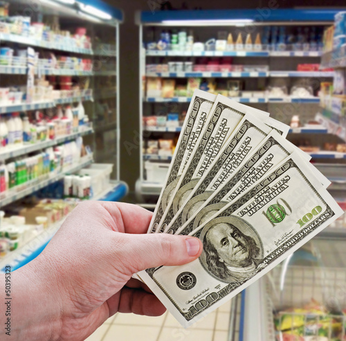 Photo: hand holding money on shopping in the supermarket hand holding money on shopping in the supermarket