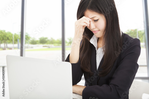 Photo: tired young businesswoman with laptop in the office tired young businesswoman with laptop in the office