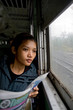 Young woman reading a newspaper on a train.