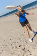 Healthy Senior Woman Playing Frisbee at Beach