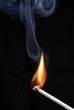 Encendiendo un cerillo,fósforo encendido en fondo negro.