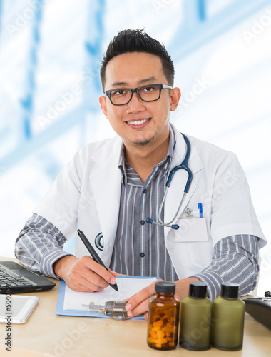 Photo: Asian medical doctor working on his desk Asian medical doctor working on his desk