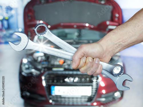 Photo: Close up of a hand with tools in front of an engine bay Close up of a hand with tools in front of an engine bay