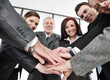 Group of happy smiling executives placing their hands together