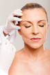 cosmetic surgeon injecting mid age woman