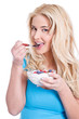 Junge blonde Frau isst genüsslich ihr Müsli