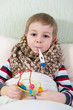 Sick little boy lying in bed with thermometer