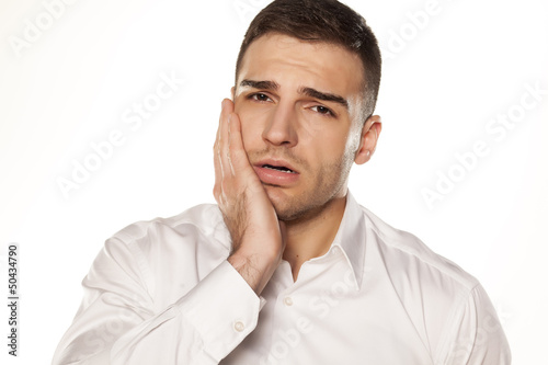 Photo: a young man with a toothache on white background a young man with a toothache on white background