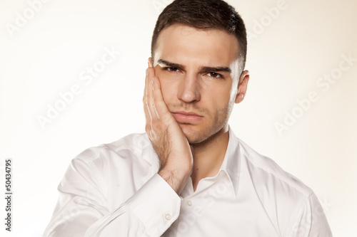 Photo: a young man with a toothache on white background a young man with a toothache on white background