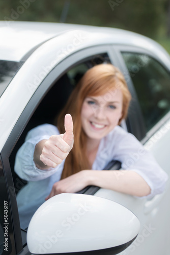 Photo: glückliche frau im auto zeigt daumen hoch glückliche frau im auto zeigt daumen hoch