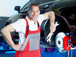 Smiling motor mechanic shows his work tools in front of a brake