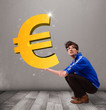 Good-looking boy holding a big 3d gold euro sign