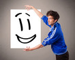 Young boy holding smiley face drawing