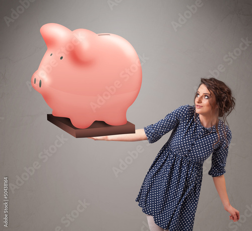 Photo: Young girl holding a huge savings piggy bank Young girl holding a huge savings piggy bank