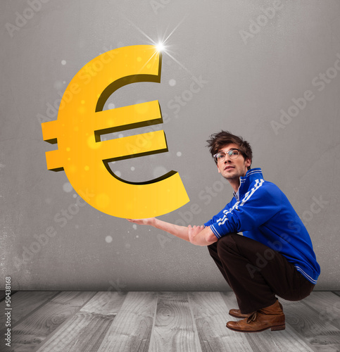 Photo: Good-looking boy holding a big 3d gold euro sign Good-looking boy holding a big 3d gold euro sign